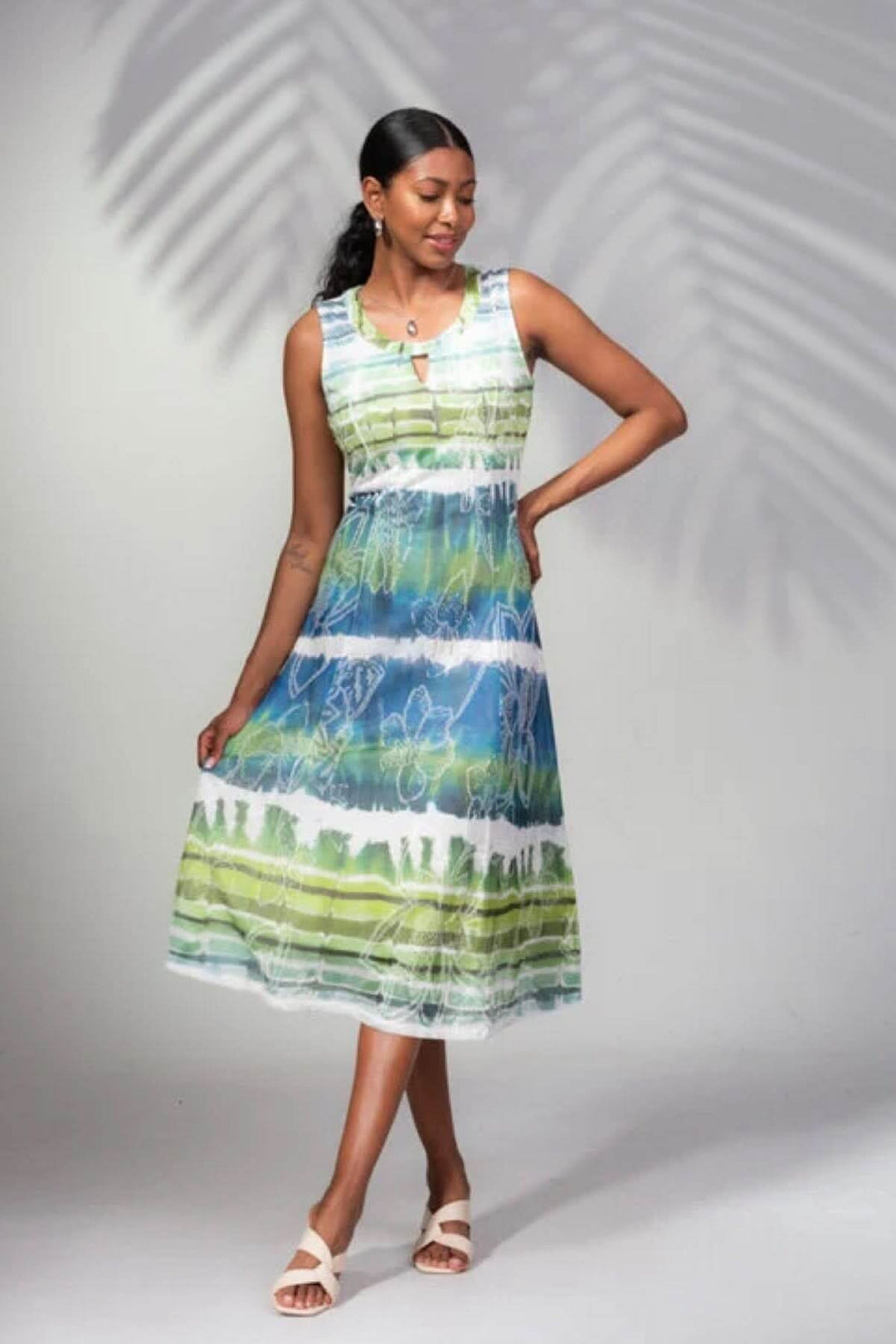 Femme portant une robe sans manches à imprimé rayé multicolore, idéale pour l'été avec une coupe midi.