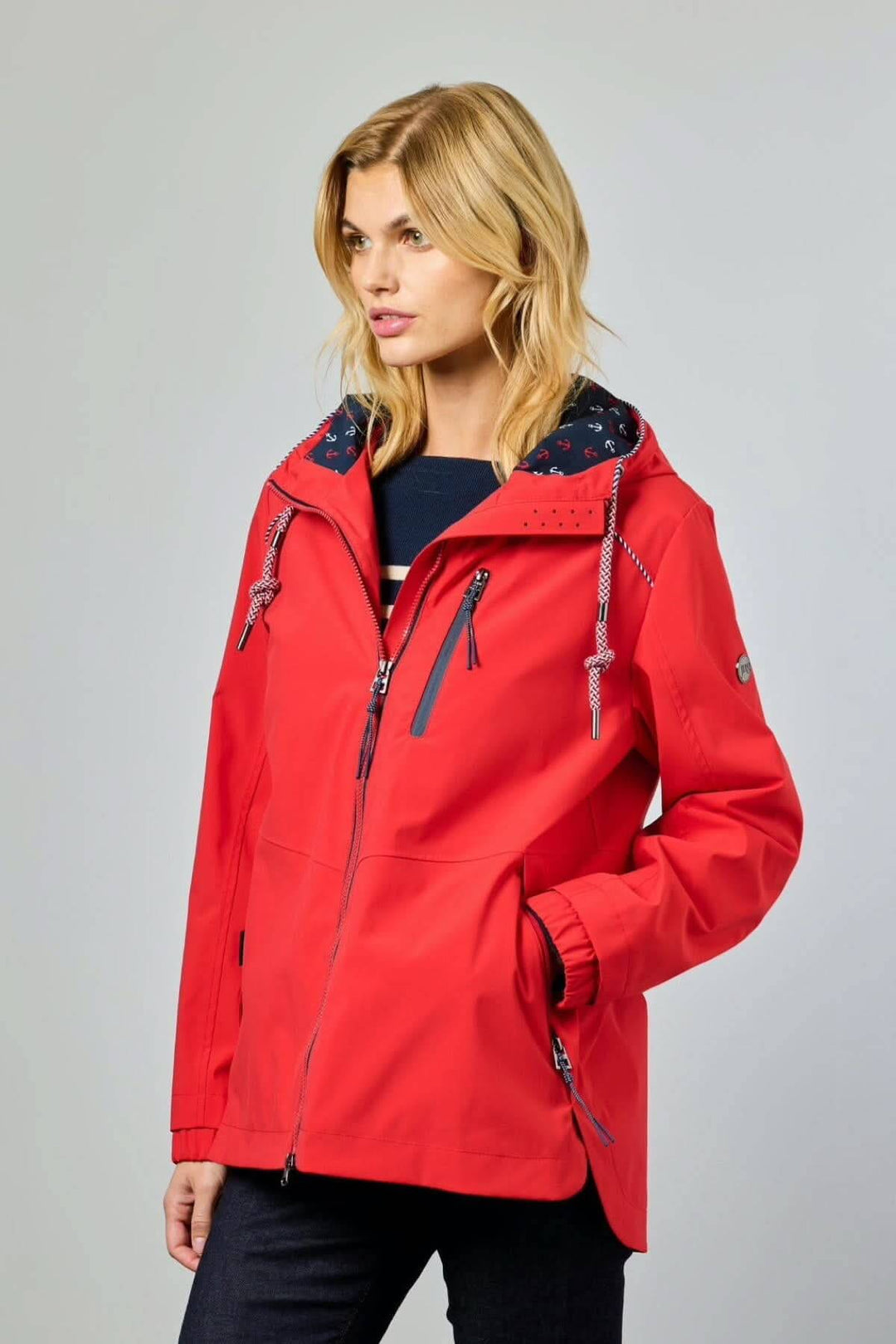 Femme portant une veste rouge 2290-88. Décris moi le produit en français, veste chic avec capuche et fermetures éclair.