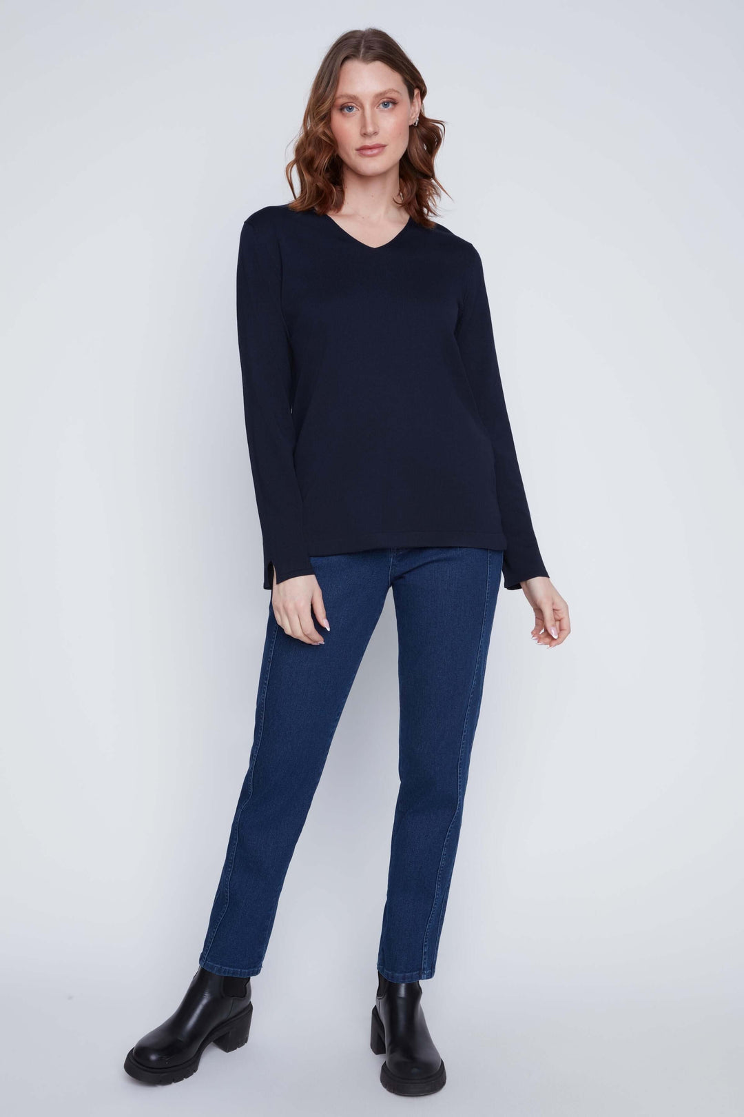 Chandail col V à manches longues, coupe fluide, associé à un jean et des bottines, look chic et minimaliste.