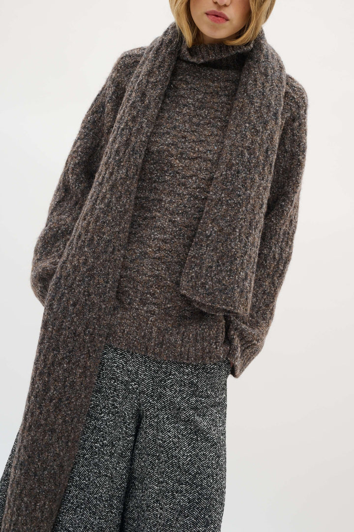 Foulard Graia en maille texturée, épais et long, apportant chaleur et style moderne, porté sur un manteau pour une allure élégante.