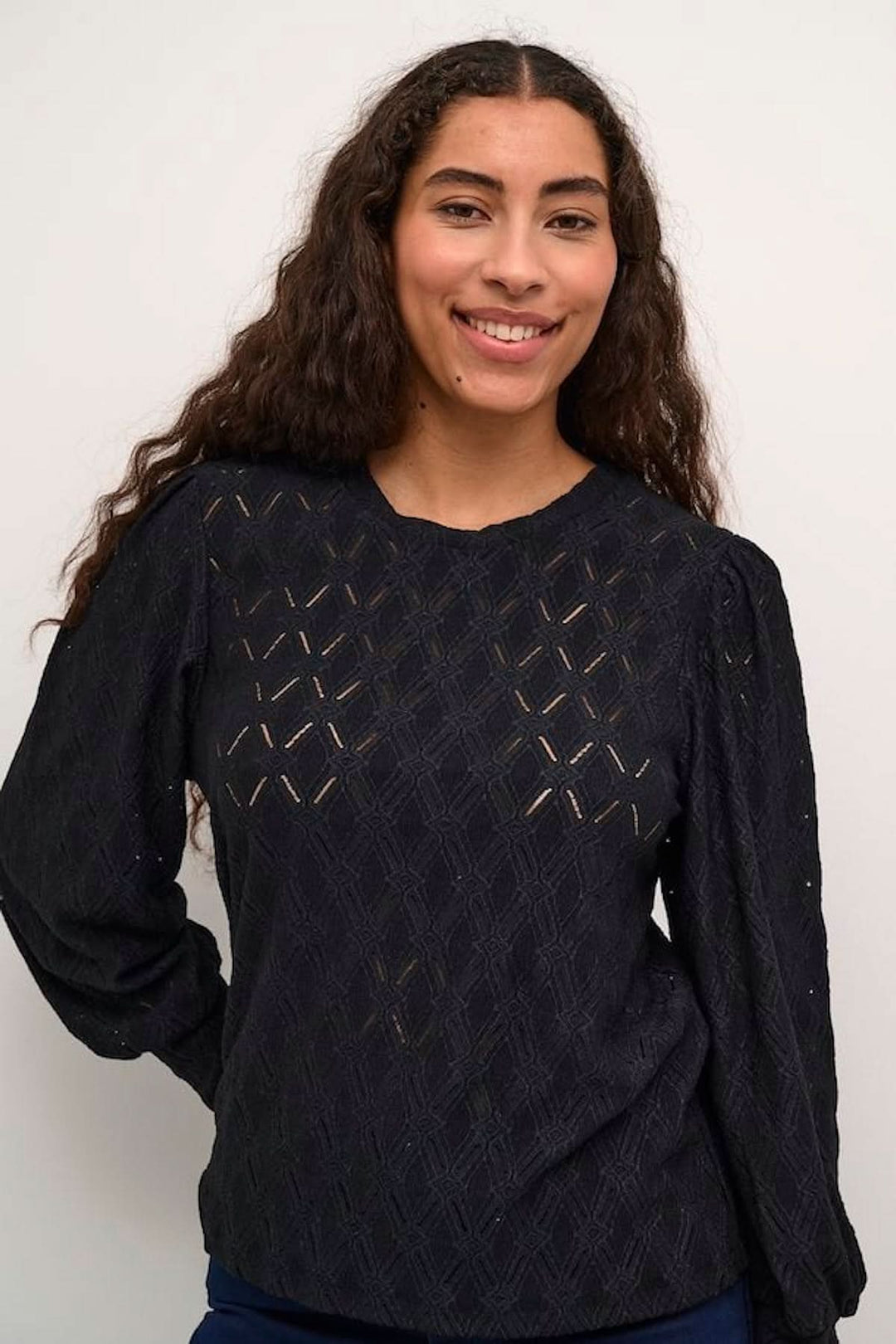 Blouse noire texturée avec motifs ajourés, manches longues bouffantes, look chic et décontracté.