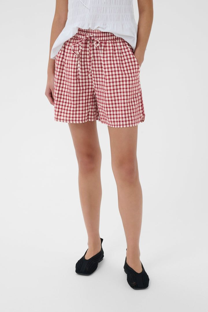 Femme portant le Bermuda Bigi à carreaux taille élastiquée, léger et confortable, avec cordon de serrage et poches latérales.