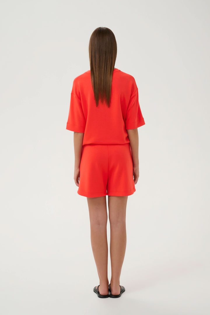 Femme portant le Bermuda Hennieh en molleton rouge, vue arrière, coupe droite, tissu doux et extensible, taille élastique.