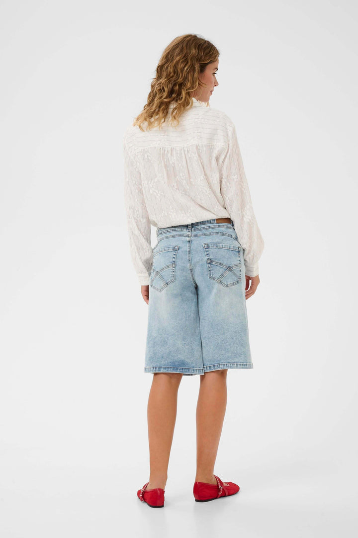 Femme portant le Bermuda Joani en denim, coupe droite, longueur genou, vue de dos, mode estivale décontractée et soignée.