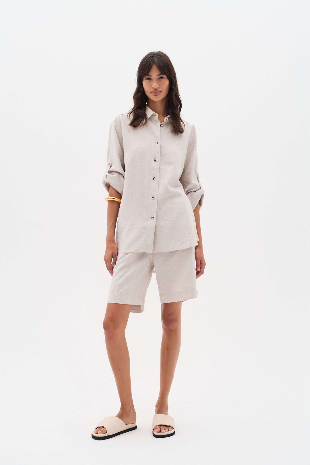 Femme portant un ensemble en lin, chemise beige et bermuda, idéal pour les journées chaudes d'été.