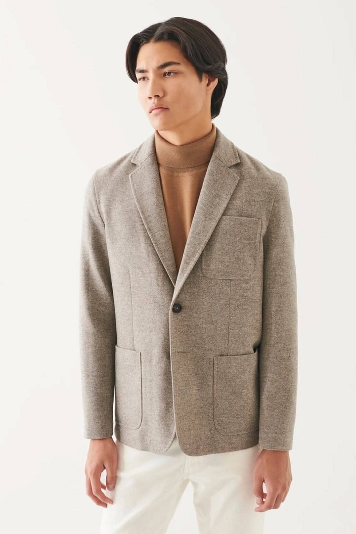 Blazer en laine à deux boutons, couleur beige, style oversize, poches plaquées, associé à un col roulé.