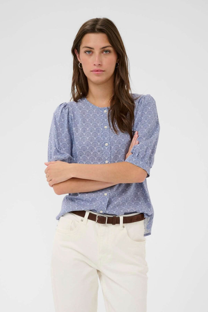 Femme portant Blouse Azra à imprimé fin avec manches légèrement bouffantes pour une allure féminine et facile à porter.