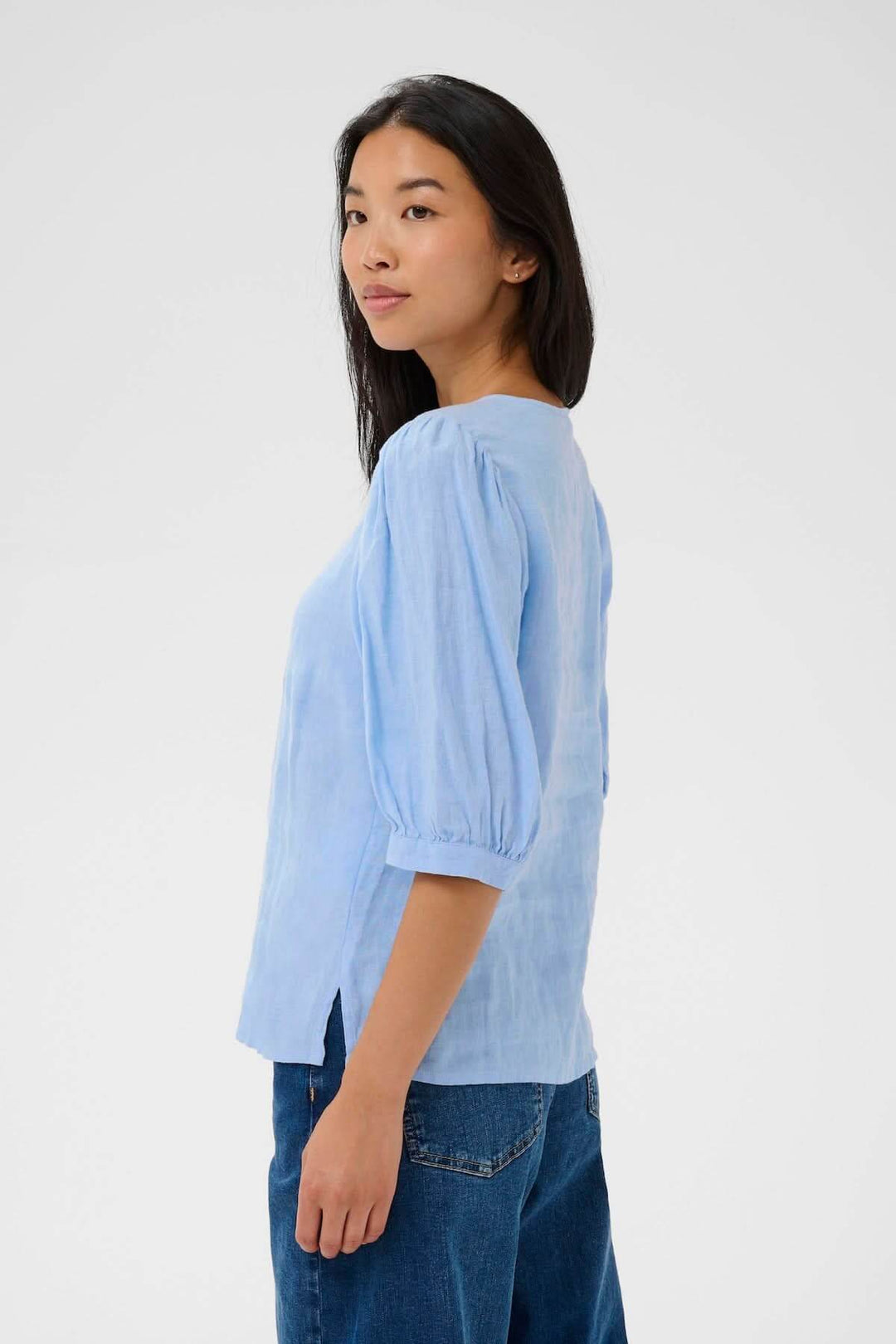 Femme portant la Blouse Azra bleue avec manches bouffantes et coupe droite, tenant une allure casual et élégante.