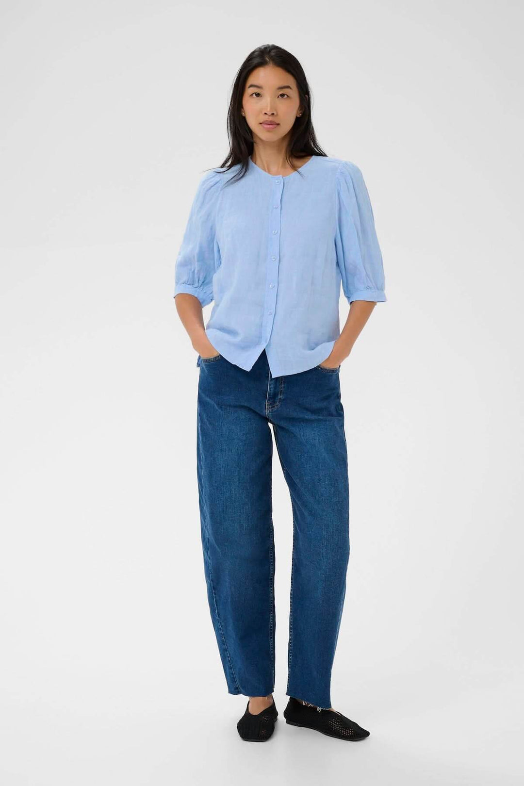 Femme portant la Blouse Azra avec coupe droite et manches légèrement bouffantes, style intemporel, encolure ronde.