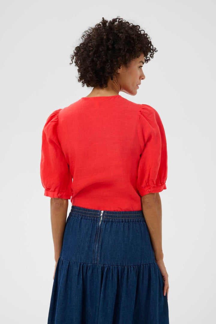 Femme portant Blouse Azra rouge avec manches bouffantes, vue de dos. Style intemporel et féminin, idéal pour tenues décontractées et soignées.