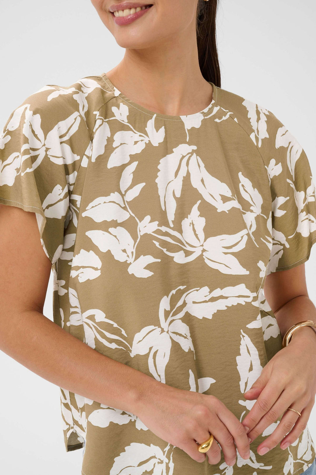 Femme portant la Blouse Marlo fluide à imprimé feuillage avec manches courtes, encolure ronde et ourlet arrondi.
