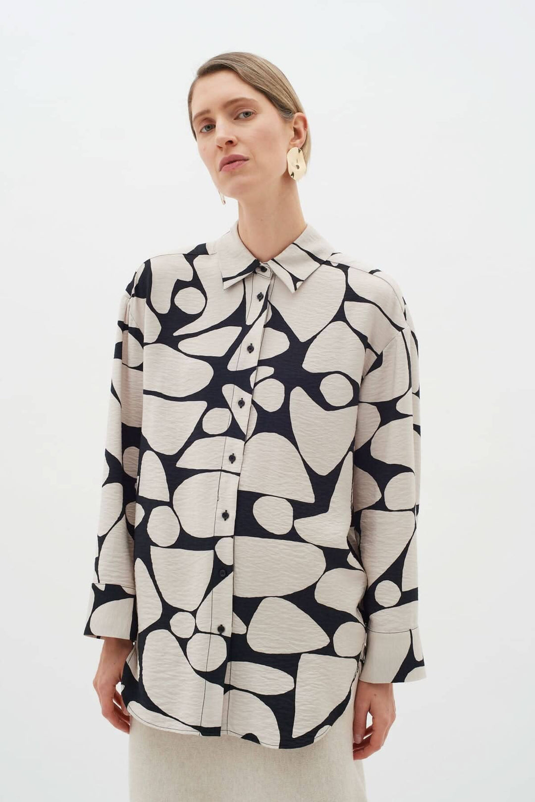 Blouse Metta beige et noir à col classique et motifs abstraits, portée par un mannequin.