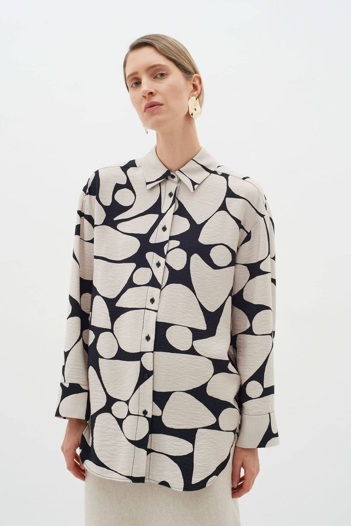 Blouse Metta beige et noir à col classique et motifs abstraits, portée par un mannequin.