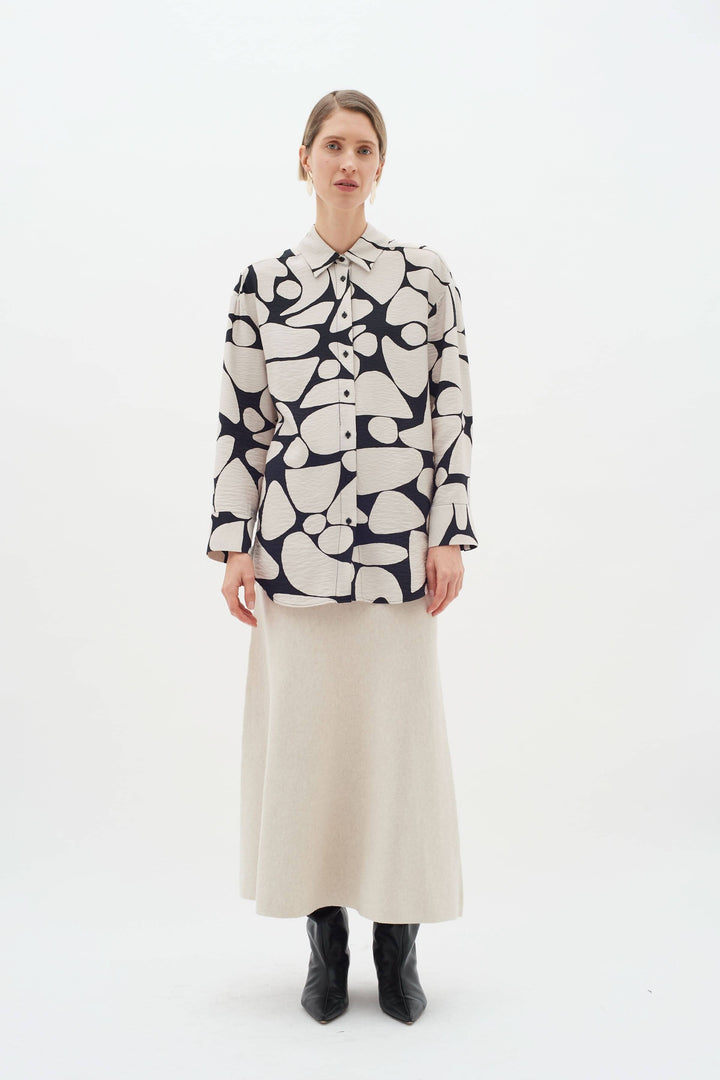 Blouse Metta à col classique, imprimé abstrait, portée avec une jupe longue et des bottines, look élégant.