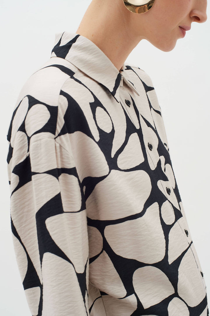 Blouse Metta avec col classique, manches longues et imprimé abstrait unique en noir et beige.