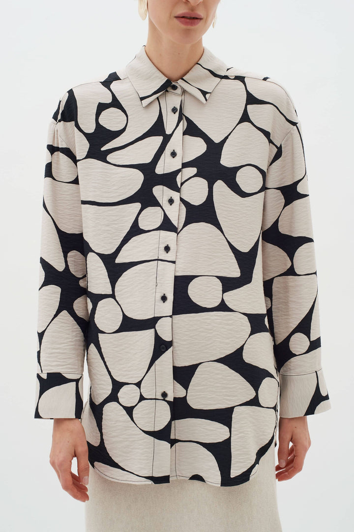 Blouse Metta à col classique, manches longues et imprimé abstrait unique, portée par un mannequin.