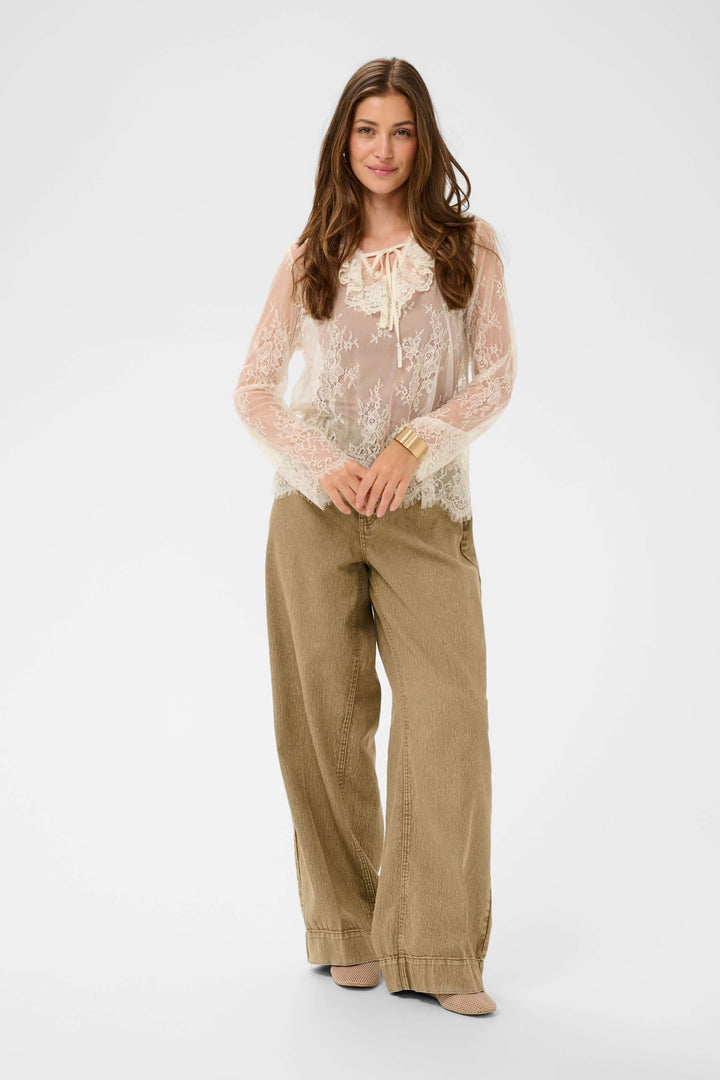 Blouse Mira en dentelle transparente à manches longues, silhouette romantique et raffinée. Décris moi le produit en français.