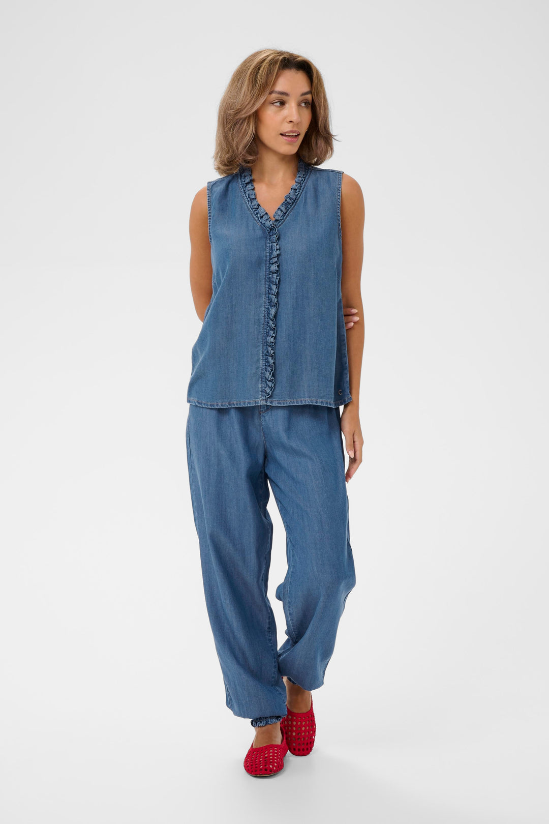 Blouse Molly sans manches denim léger avec encolure en V et détail volanté, style décontracté et féminin, tenue harmonieuse avec pantalon.