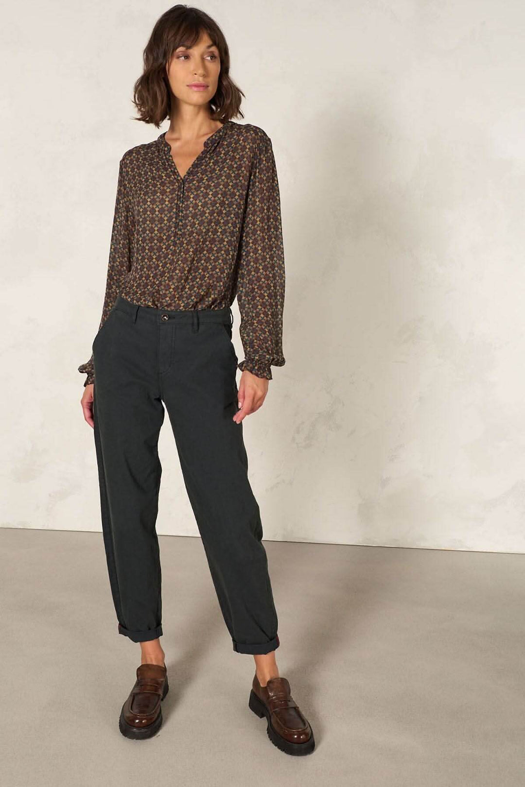 Femme portant une blouse à coupe droite avec manches longues, encolure en V et pantalon décontracté.