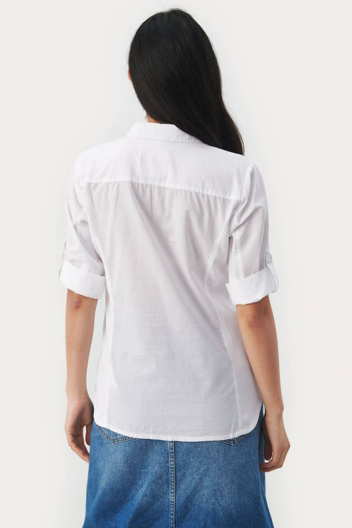 Femme portant une blouse blanche cortnia en coton, vue arrière, avec manches roulées et col classique.