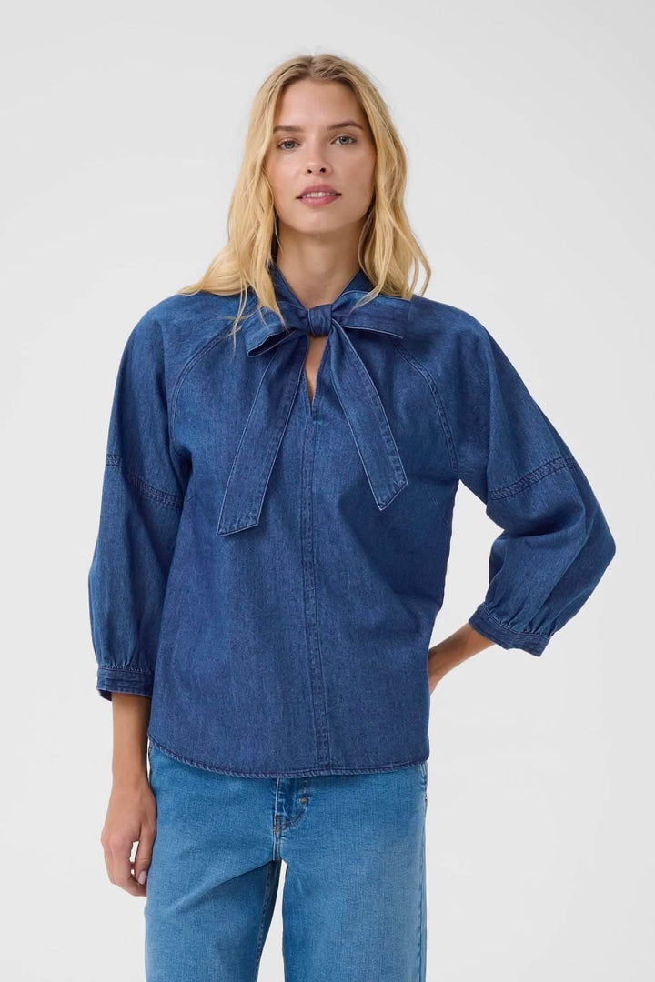 Blouse en denim avec col lavallière, manches bouffantes et coupe fluide pour un style élégant et décontracté.
