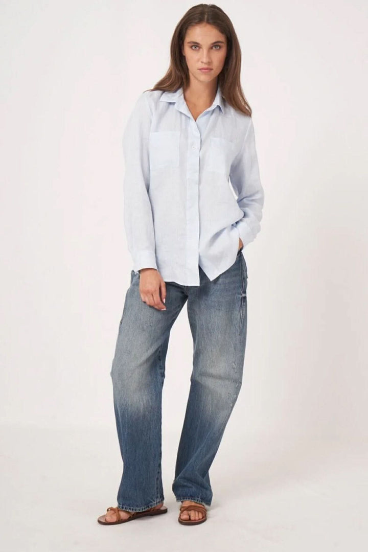 Blouse en lin fluide et intemporelle avec manches longues et col classique, portée avec un jean pour un style décontracté.