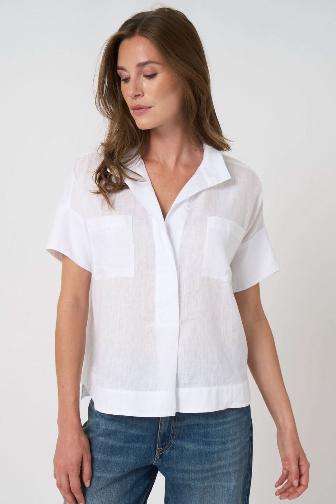 Femme portant une blouse en lin à manches chauve-souris, coupe ample, col chemise ouvert, parfaite pour un style décontracté.