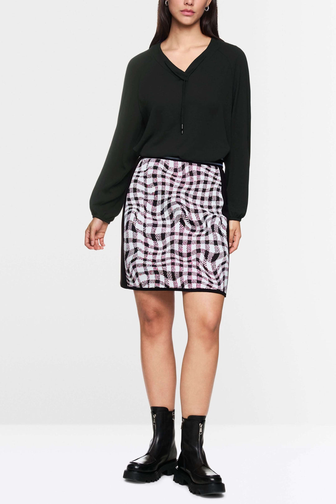 Femme portant une blouse fluide noire avec jupe imprimée, mettant en valeur l&