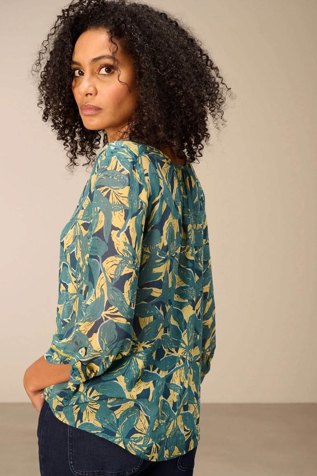Blouse fluide imprimé avec imprimé végétal audacieux et manches 3/4, coupe décontractée, portée avec un jean.