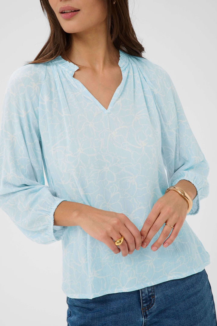 Blouse fluide à imprimé floral discret avec encolure en V et manches trois-quarts, idéal pour une élégance quotidienne.