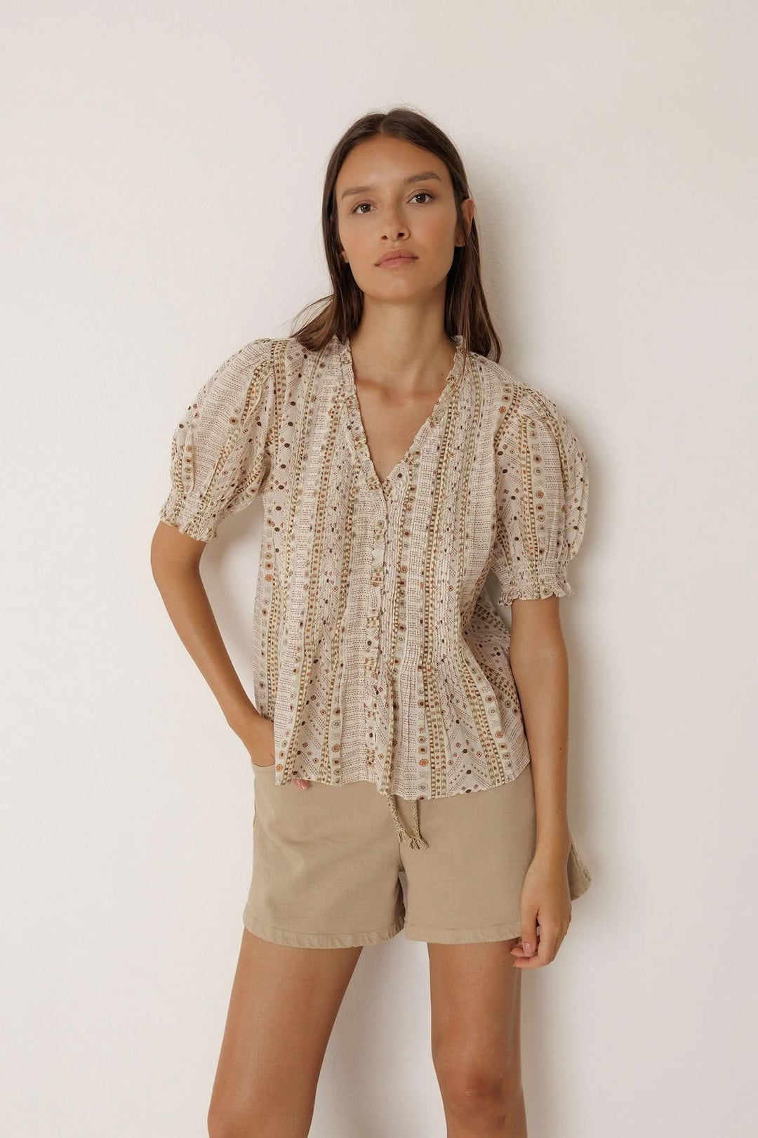 Blouse fluide imprimée à manches courtes avec encolure en V et manches bouffantes, portée par un modèle féminin.
