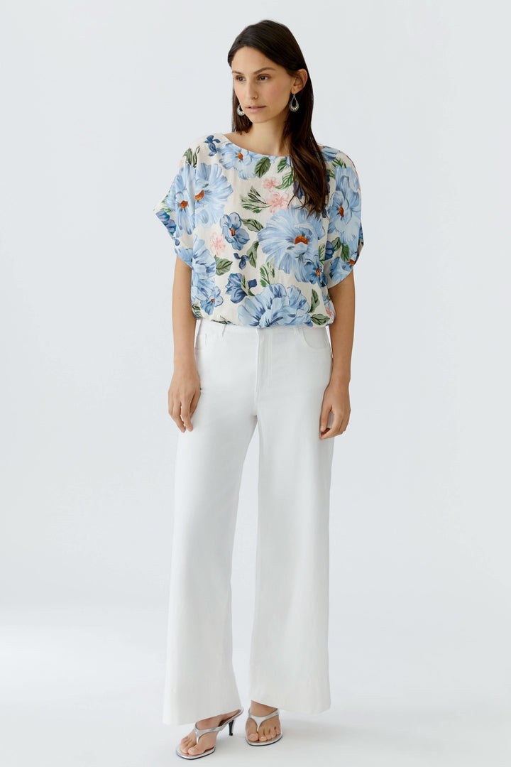 Blouse fluide à manches courtes avec imprimé fleuri portée par un modèle, idéale pour un look quotidien élégant.