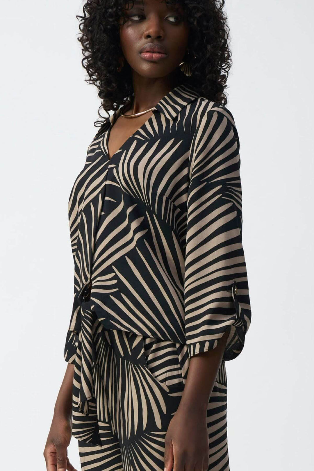 Blouse légère imprimé feuillage avec col en V, manches 3/4 et ourlet noué, style décontracté et féminin.