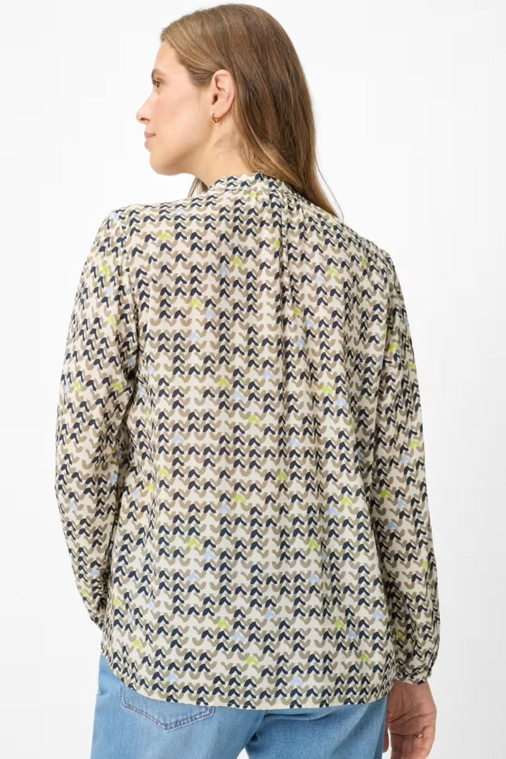 Blouse imprimée avec motif féminin, vue de dos, coupe droite, tissu léger, portée par une femme avec pantalon en denim.