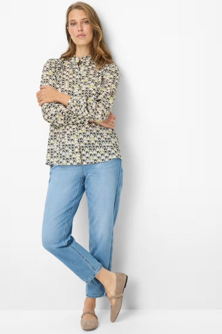 Femme portant une blouse imprimée féminine et fluide, idéale pour un look quotidien ou soigné, avec un style moderne et confortable.