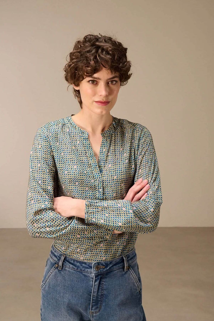 Blouse imprimée à manches longues avec imprimé graphique et encolure fendue, portée avec un jean, style moderne et polyvalent.