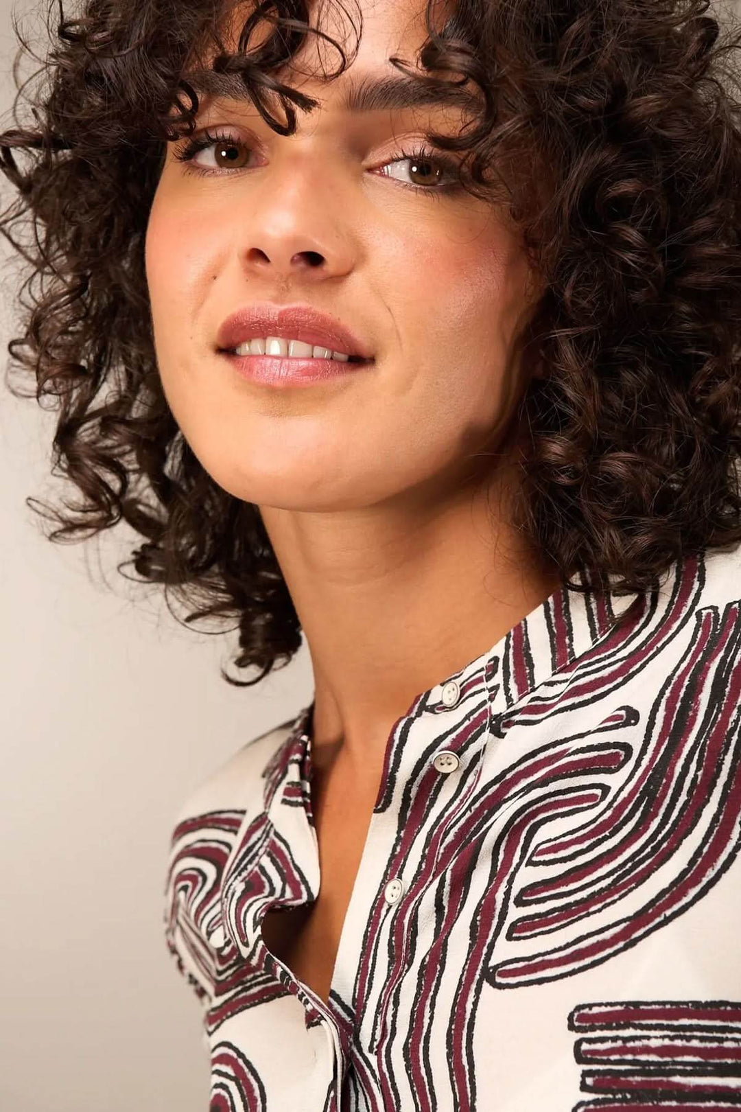 Femme portant une blouse à manches 3/4 avec encolure ronde et motifs fluides, offrant un look décontracté et élégant.