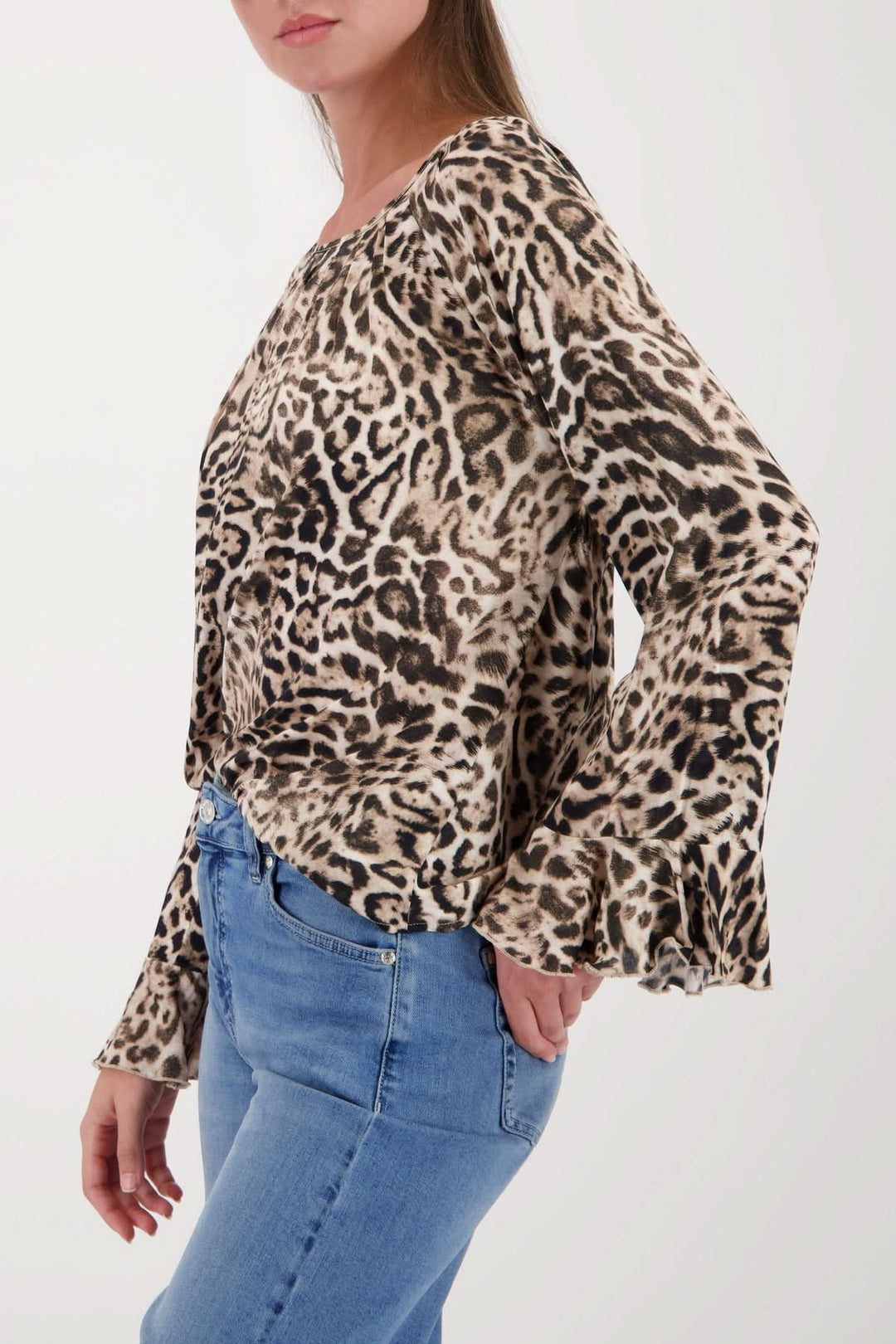Femme portant une blouse à motif léopard avec manches évasées, coupe ample, encolure ronde et finition volantée des manches.