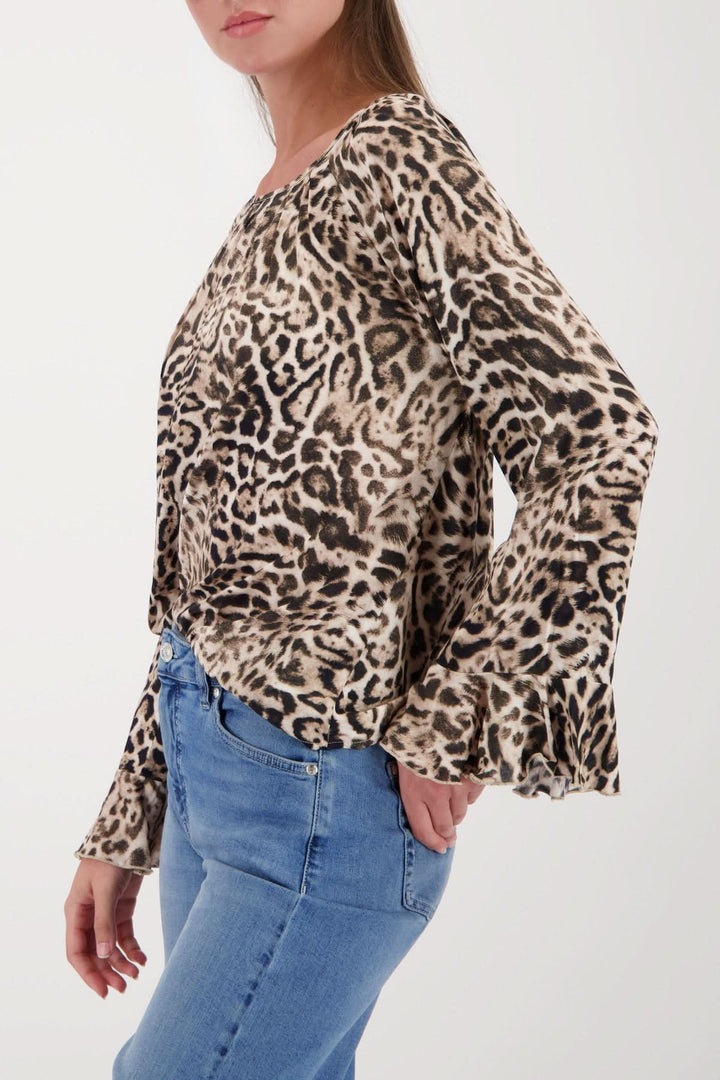 Femme portant une blouse à motif léopard avec manches évasées, coupe ample, encolure ronde et finition volantée des manches.