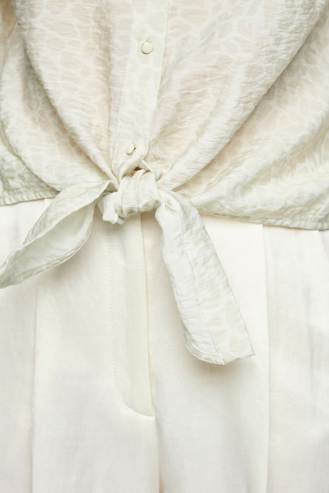 Blouse à nœuds avec motif léopard discret et manches trois-quarts élégantes.