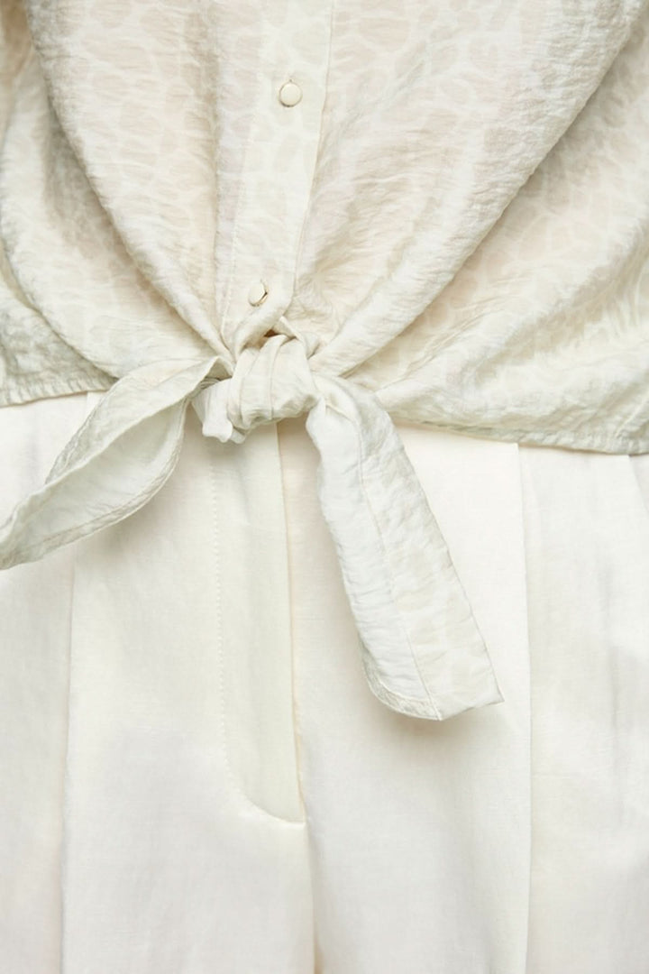 Blouse à nœuds avec motif léopard discret et manches trois-quarts élégantes.