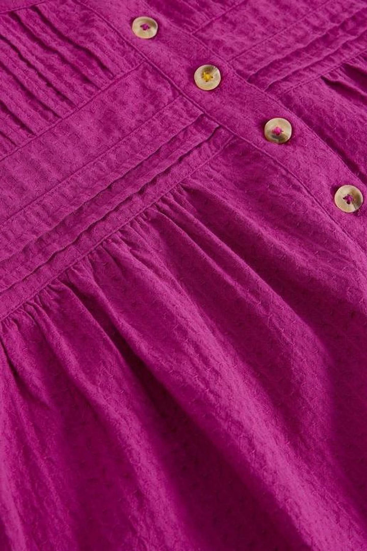 Détail en gros plan de la blouse plumetis à plastron froncé avec texture et boutons.
