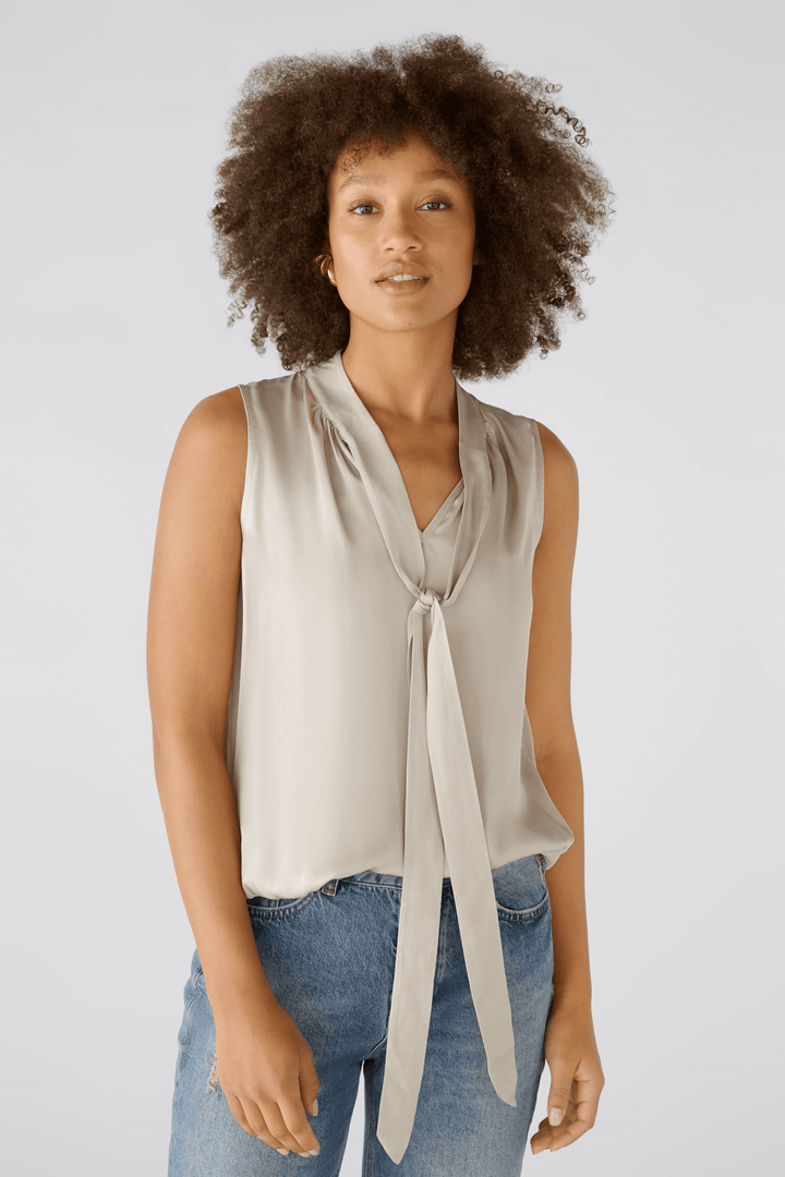 Femme portant une blouse évasée satinée avec encolure en V et ceinture élastiquée pour une silhouette flatteuse.