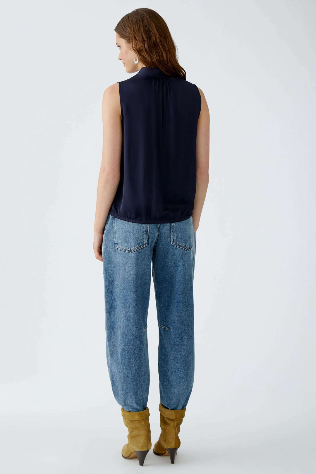Vue arrière de la Blouse évasée en satin avec texture brillante et ourlet élastiqué, portée avec un jean décontracté et des bottes camel.