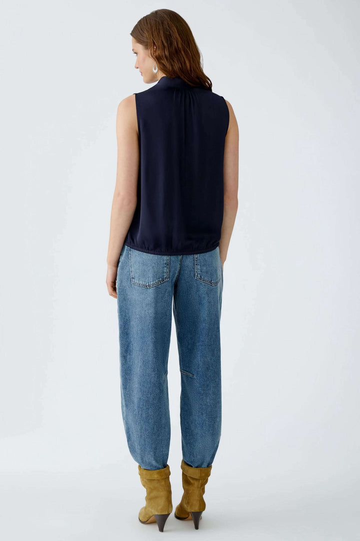 Vue arrière de la Blouse évasée en satin avec texture brillante et ourlet élastiqué, portée avec un jean décontracté et des bottes camel.