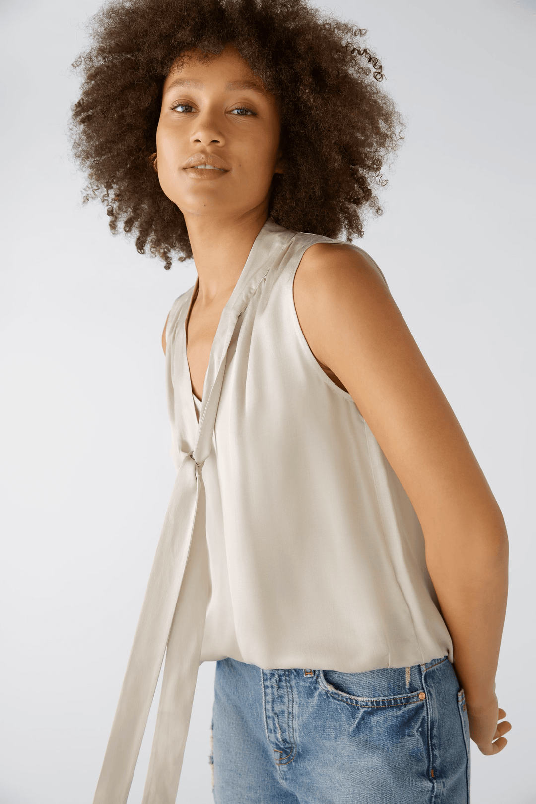 Blouse évasée satinée avec volants et ceinture élastiquée, portée par une femme, offrant une silhouette féminine et confortable.