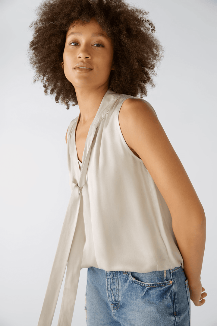 Blouse évasée satinée avec volants et ceinture élastiquée, portée par une femme, offrant une silhouette féminine et confortable.
