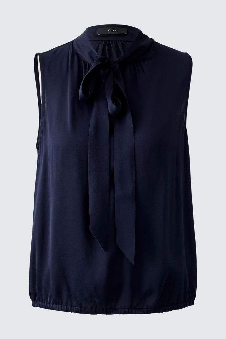 Blouse évasée bleu foncé avec texture satinée et détails élégants, offrant une silhouette flatteuse et confortable.