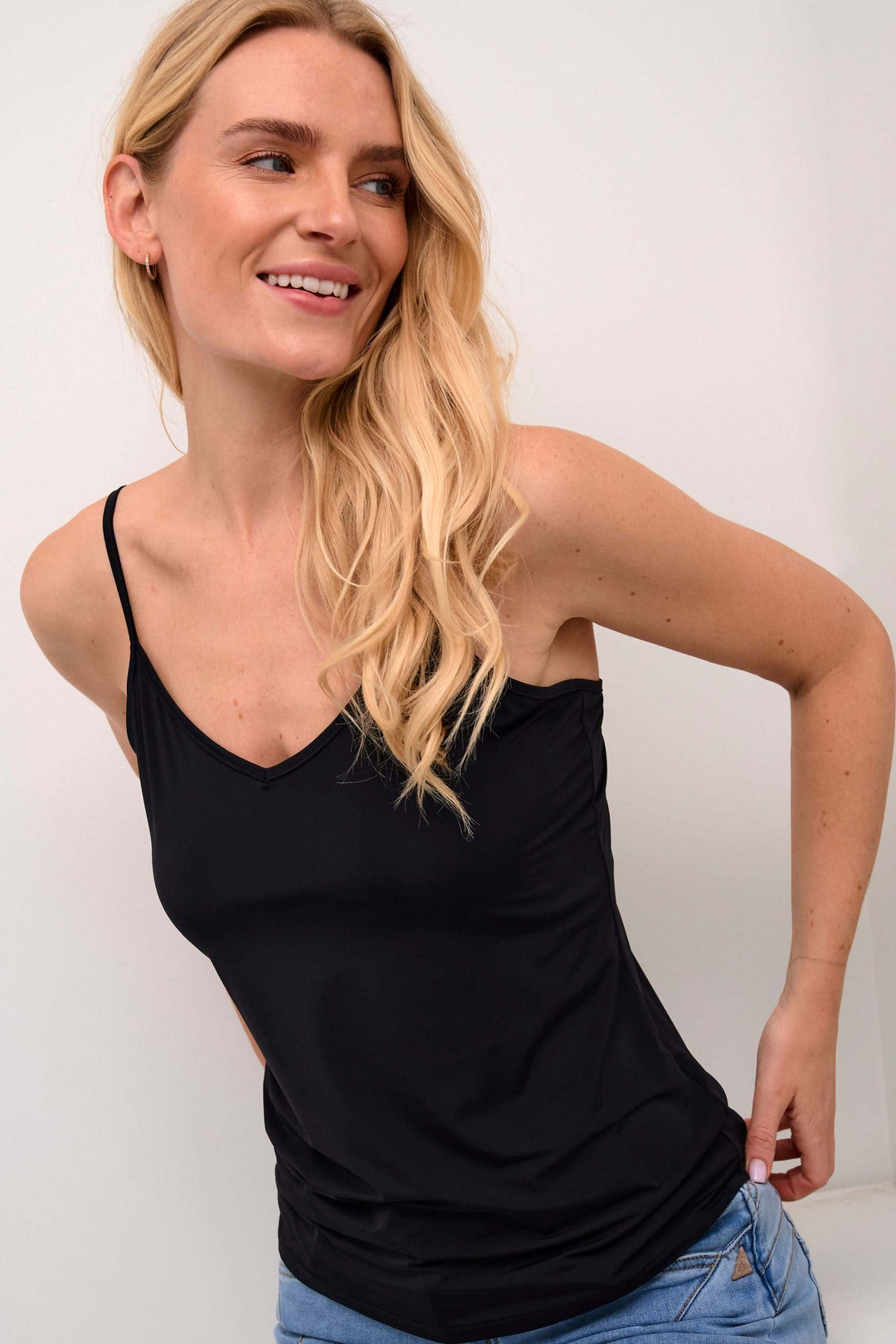 Femme portant une Camisole Lissandra noire avec décolleté en V et bretelles fines, style ajusté, idéale pour une garde-robe contemporaine.