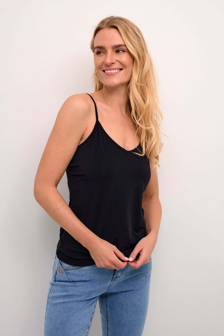 Femme portant la Camisole Lissandra noire avec bretelles fines, coupe ajustée, style polyvalent.